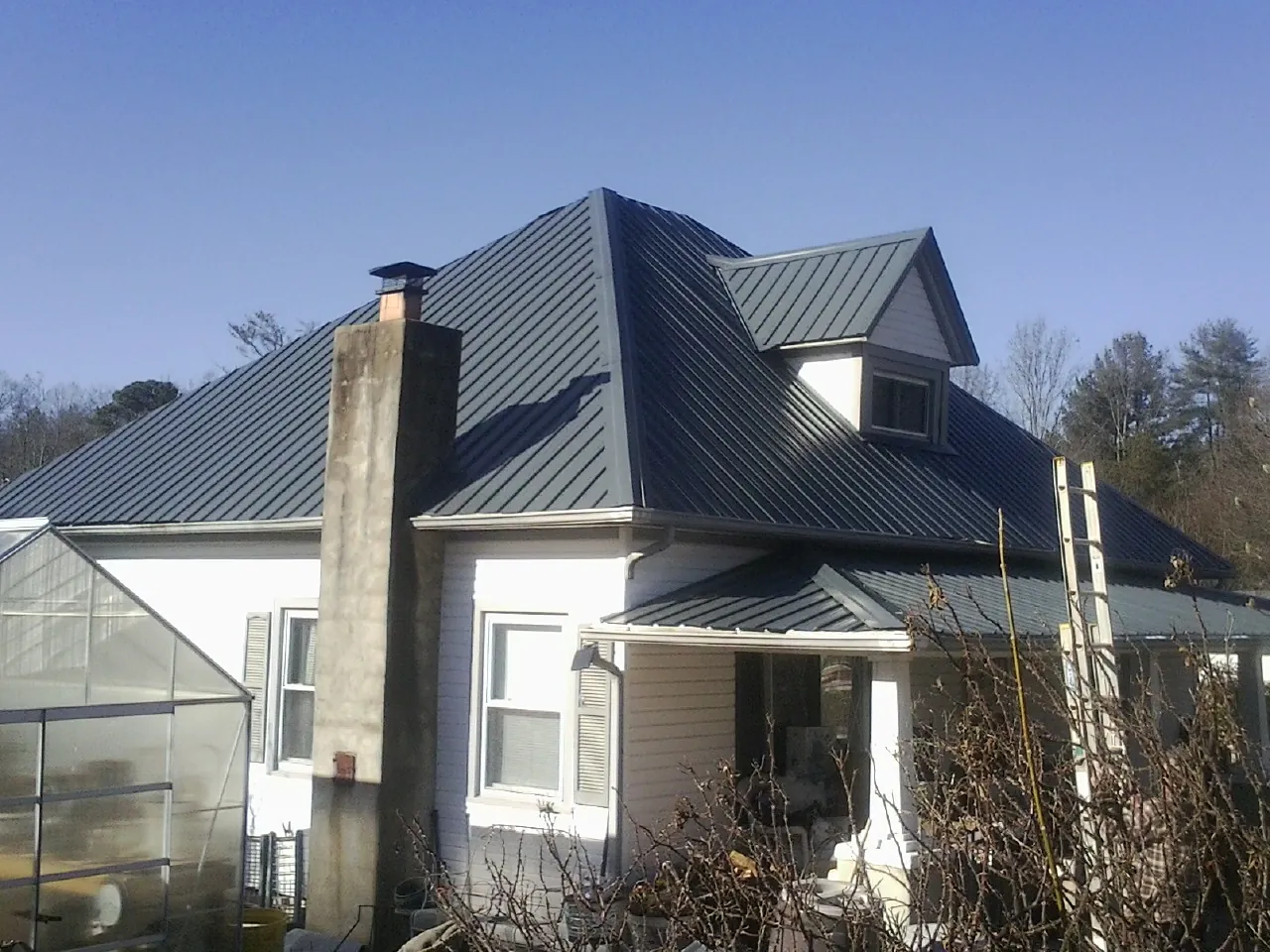 Dark blue standing seam metal roof on a white farmhouse with dormer — Slate & Tile Roof Repair by Roofing Brothers in Pompeys Pillar