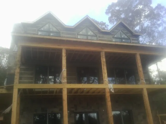 Dormers and porch framing on a large log home under construction — Roof Coating work by our crew in Pompeys Pillar