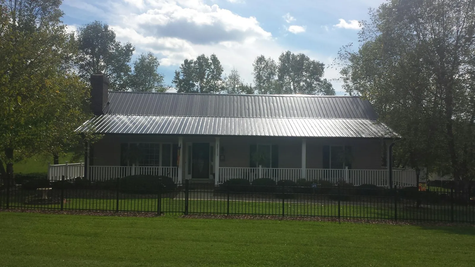 Gray metal roof on a brick ranch with a full width front porch — Gutter Guard Installation work by our crew in Pompeys Pillar