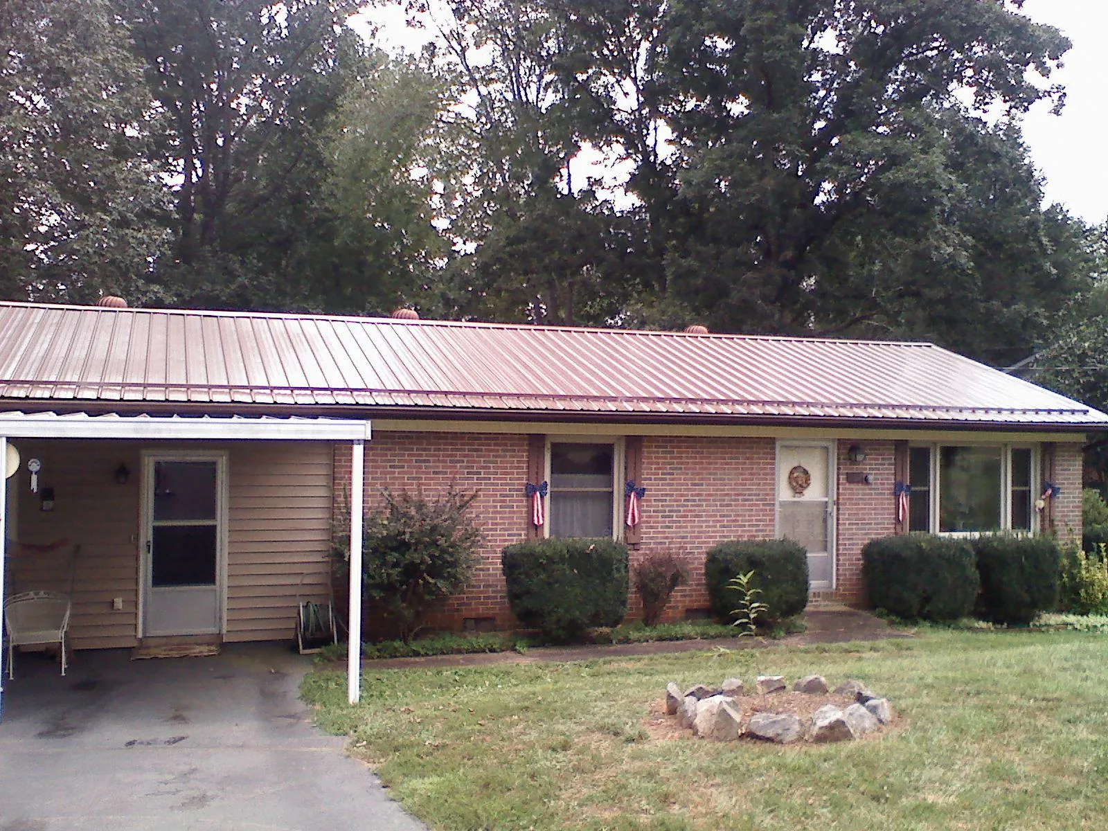 Bronze metal roof and carport on a brick ranch home — Roof Repair work by our crew in Pompeys Pillar