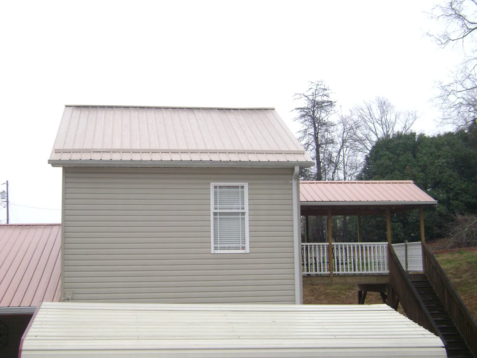 Tan metal roofs on a two story addition and attached porch, from a Roof Replacement job in Pompeys Pillar