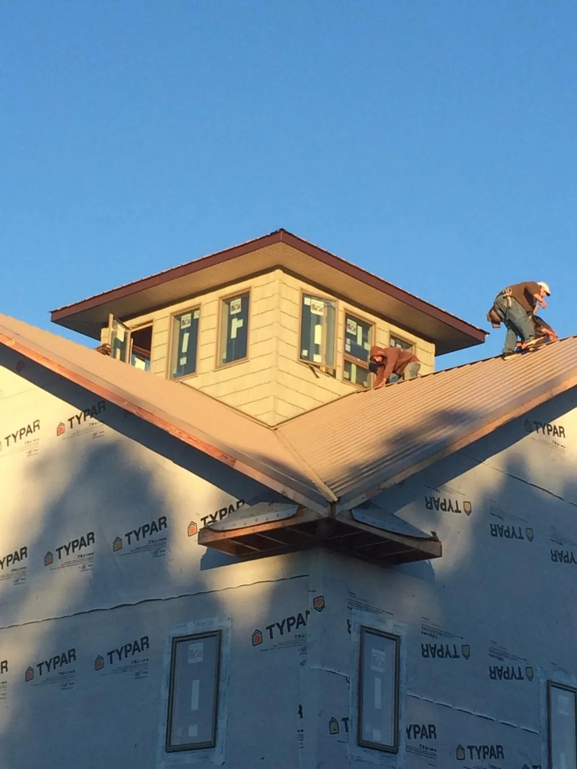 Roofers working around a rooftop cupola on a new metal roof at sunset — Roof Waterproofing in Pompeys Pillar by Roofing Brothers